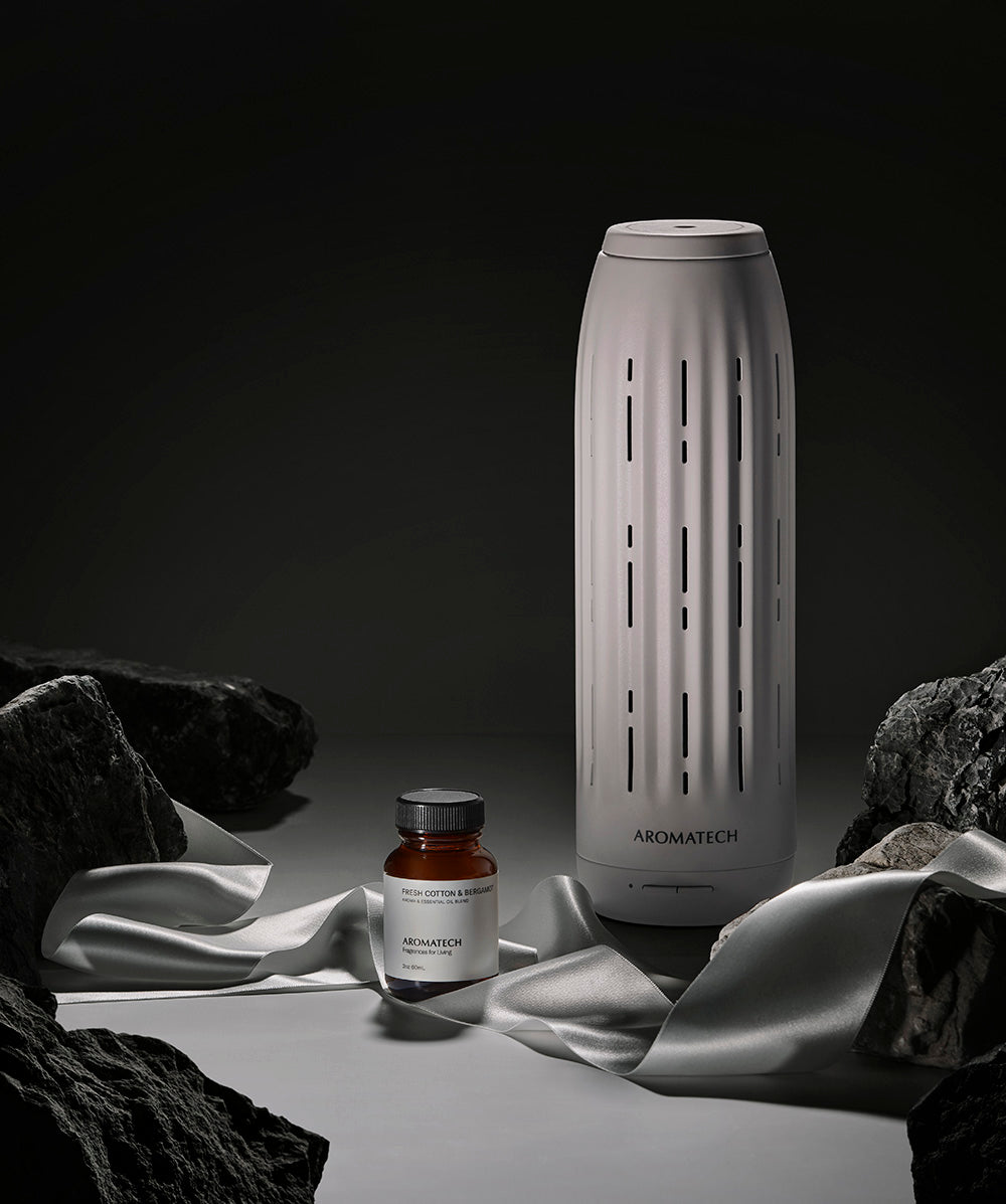 Aromatech diffuser and bottle on a dark background with draped fabric