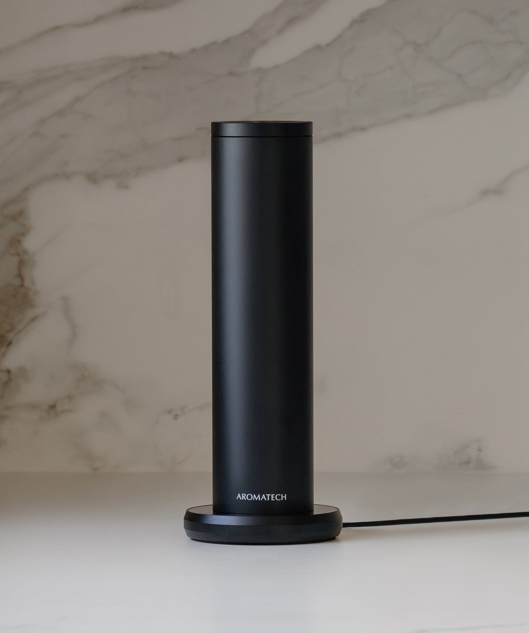 Sleek black AroMini BT Plus diffuser against a modern marble backdrop